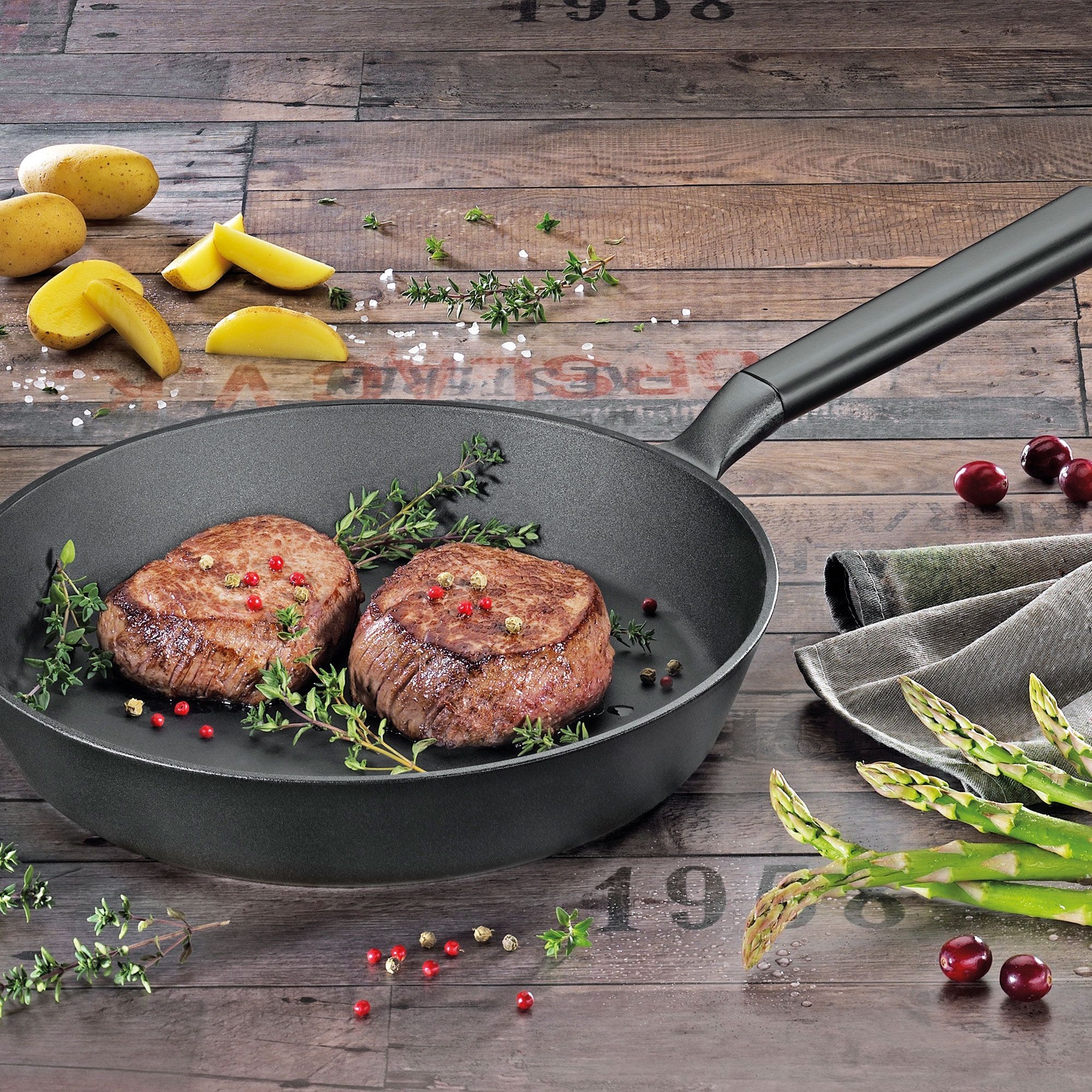 Frying pan with steaks, potatoes and asparagus