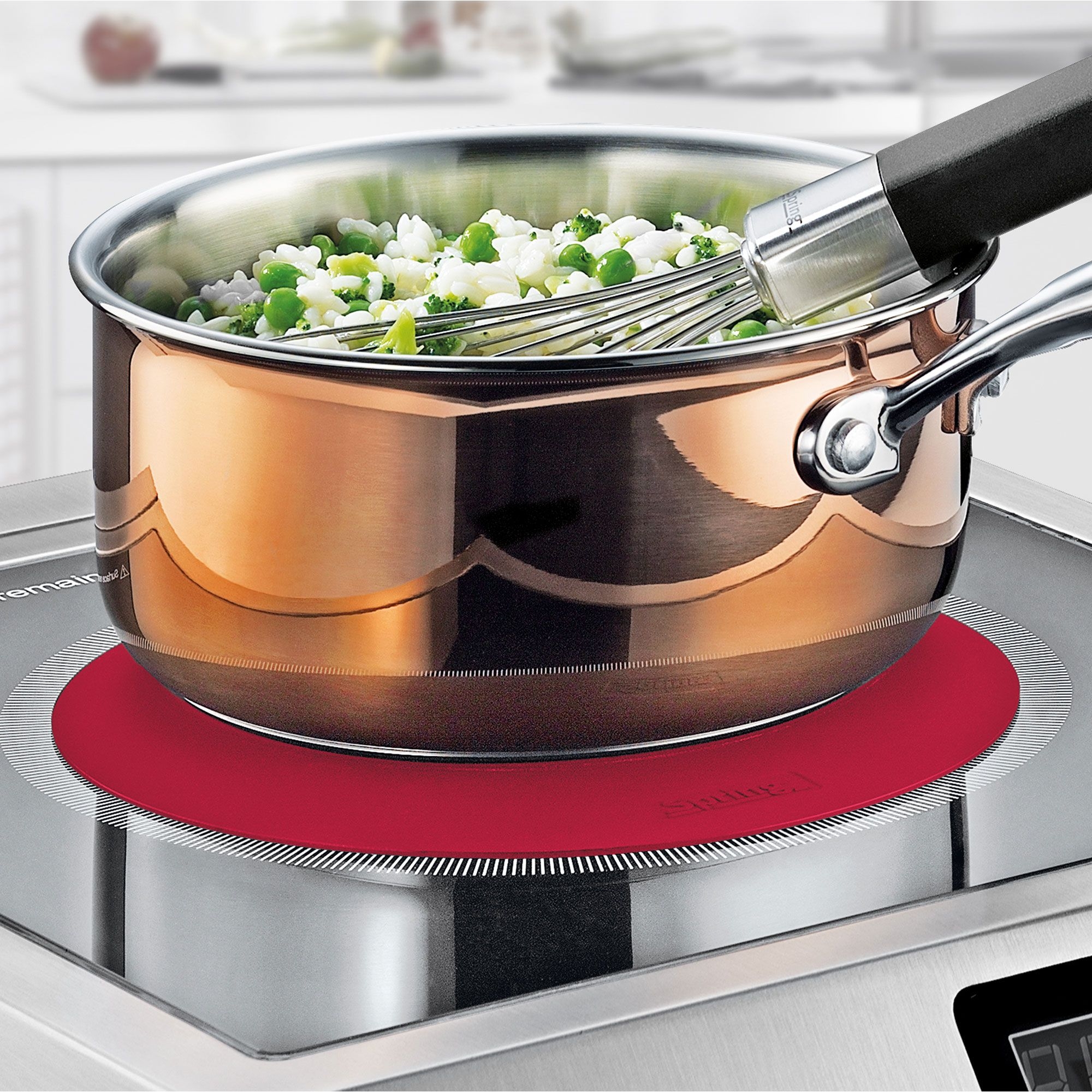 Kupfertopf mit Gemüse und Schneebesen auf Herdplatte